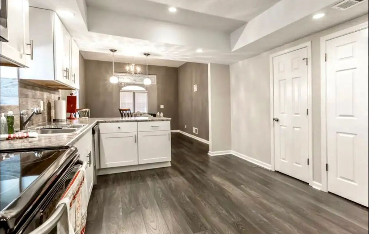 A bright and inviting view of the kitchen island with stylish pendant lights, seamlessly transitioning to the adjoining dining area. The space feels open and communal, perfect for cooking together, hosting dinner parties, or enjoying a morning coffee. The image conveys both the kitchen and dining area's connection.