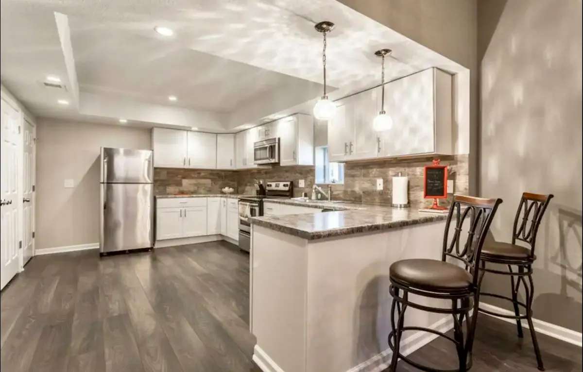 A spacious, welcoming kitchen with a central island, stainless steel appliances, and stylish pendant lighting. The setup is perfect for group cooking and gatherings, offering plenty of room for social interaction and meal preparation.